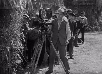 Movie still from “King Kong” (1933), directed by Merian C. Cooper – A group of men standing next to each other on a dirt road; Wide shot, High angle