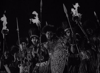 Movie still from “King Kong” (1933), directed by Merian C. Cooper – A black and white photo of a group of people in costume; Medium shot, High angle