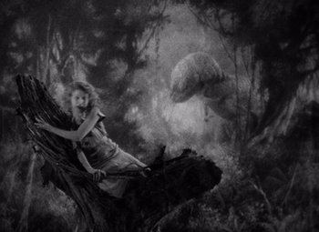 Movie still from “King Kong” (1933), directed by Merian C. Cooper – A woman sitting on a tree in the woods; Wide shot, High angle