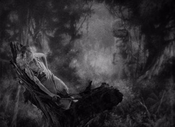 Movie still from “King Kong” (1933), directed by Merian C. Cooper – A woman is sitting on top of a tree branch; Wide shot, High angle