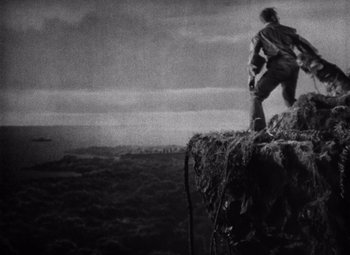 Movie still from “King Kong” (1933), directed by Merian C. Cooper – A man standing on top of a hill; Extreme Wide shot, Low angle