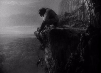 Movie still from “King Kong” (1933), directed by Merian C. Cooper – A man sitting on top of a rock on top of a mountain; Extreme Wide shot, Low angle