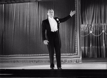 Movie still from “King Kong” (1933), directed by Merian C. Cooper – A black and white photo of a man in a tuxedo on a stage; Medium shot, Low angle