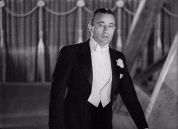 Movie still from “King Kong” (1933), directed by Merian C. Cooper – A man in a tuxedo standing in front of a curtain; Medium shot, Low angle