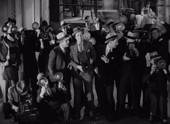 Movie still from “King Kong” (1933), directed by Merian C. Cooper – A black and white photo of a group of men taking pictures; Wide shot, High angle