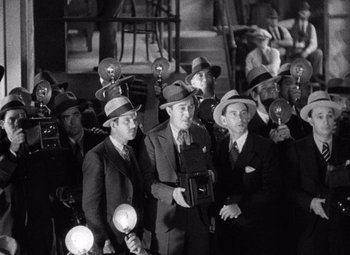 Movie still from “King Kong” (1933), directed by Merian C. Cooper – A black and white photo of a group of men in suits and hats; Medium shot, High angle