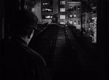 Movie still from “King Kong” (1933), directed by Merian C. Cooper – A man standing on the side of a train track at night; Medium shot, High angle
