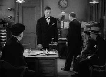 Movie still from “King Kong” (1933), directed by Merian C. Cooper – A man in a suit standing in front of a desk; Medium shot, Over the shoulder angle