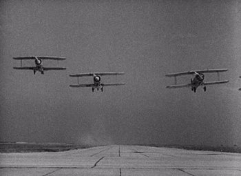 Movie still from “King Kong” (1933), directed by Merian C. Cooper – A group of planes flying in the air on a cloudy day; Extreme Wide shot, Low angle