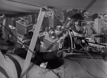 Movie still from “King Kong” (1933), directed by Merian C. Cooper – Two men are sitting in the cockpit of an airplane; Medium shot, High angle