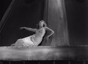 Movie still from “King Kong” (1933), directed by Merian C. Cooper – A woman in a white dress on top of a metal structure; Wide shot, Low angle