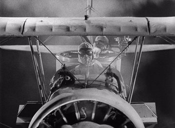 Movie still from “King Kong” (1933), directed by Merian C. Cooper – An old photo of two people in a biplane; Wide shot, Overhead angle