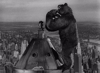 Movie still from “King Kong” (1933), directed by Merian C. Cooper – A gorilla standing on top of a building in the middle of a city; Wide shot, Overhead angle