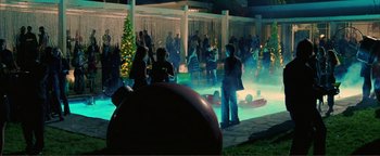 Movie still from “Kiss Kiss Bang Bang” (2005), directed by Shane Black – A group of people standing around a pool at night; Extreme Wide shot, High angle