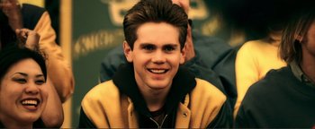 Movie still from “Kiss Kiss Bang Bang” (2005), directed by Shane Black – A young man smiling for the camera while wearing a yellow jacket; Close Up shot, Over the shoulder angle
