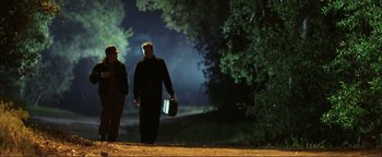 Movie still from “Kiss Kiss Bang Bang” (2005), directed by Shane Black – A man and a woman walking down a dirt road at night; Wide shot, Low angle