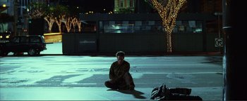 Movie still from “Kiss Kiss Bang Bang” (2005), directed by Shane Black – A man sitting on the ground in the middle of the night; Wide shot, High angle