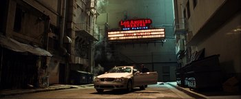Movie still from “Kiss Kiss Bang Bang” (2005), directed by Shane Black – A car parked on the side of the road in front of a movie theater; Extreme Wide shot, High angle
