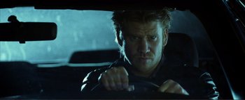 Movie still from “Kiss Kiss Bang Bang” (2005), directed by Shane Black – A person in a car holding a steering wheel; Close Up shot, Low angle