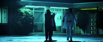 Movie still from “Kiss Kiss Bang Bang” (2005), directed by Shane Black – Two people are silhouetted against a building at night; Wide shot, Low angle