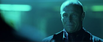 Movie still from “Kiss Kiss Bang Bang” (2005), directed by Shane Black – An older man in a suit and tie in a dark room; Close Up shot, Low angle