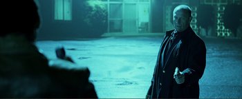 Movie still from “Kiss Kiss Bang Bang” (2005), directed by Shane Black – A man standing in a parking lot at night; Medium shot, Over the shoulder angle