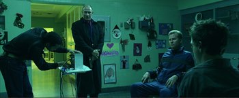 Movie still from “Kiss Kiss Bang Bang” (2005), directed by Shane Black – A man standing next to another man in front of a wall; Medium shot, Over the shoulder angle