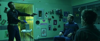 Movie still from “Kiss Kiss Bang Bang” (2005), directed by Shane Black – A man in a blue suit is sitting in front of a wall; Medium shot, Over the shoulder angle