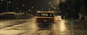 Movie still from “Kiss Kiss Bang Bang” (2005), directed by Shane Black – A car driving down a wet street at night; Wide shot, Low angle