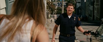 Movie still from “Knight and Day” (2010), directed by James Mangold – A man in a police uniform walking down a street; Medium shot, Over the shoulder angle