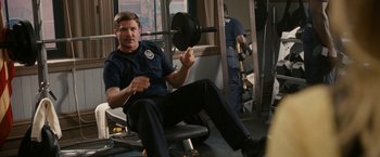 Movie still from “Knight and Day” (2010), directed by James Mangold – A police officer lifting a barbell in a gym; Medium shot, Over the shoulder angle
