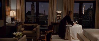 Movie still from “Knight and Day” (2010), directed by James Mangold – A woman sitting at a table in front of a large window; Wide shot, Over the shoulder angle