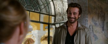 Movie still from “Knight and Day” (2010), directed by James Mangold – A man smiling for a picture in front of a window; Close Up shot, Over the shoulder angle