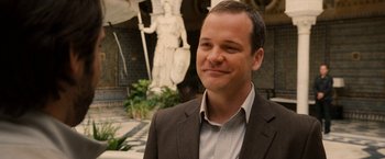 Movie still from “Knight and Day” (2010), directed by James Mangold – A man wearing a suit and smiling for the camera; Close Up shot, Over the shoulder angle
