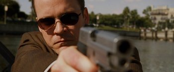 Movie still from “Knight and Day” (2010), directed by James Mangold – A person holding a gun with trees in the background; Close Up shot, Low angle