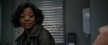 Movie still from “Knight and Day” (2010), directed by James Mangold – A woman in a gray coat is standing in front of a window; Close Up shot, Over the shoulder angle