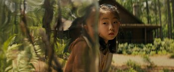 Movie still from “Knock at the Cabin” (2023), directed by M. Night Shyamalan – A young girl looking through a window in a tree; Medium shot, High angle