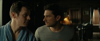 Movie still from “Knock at the Cabin” (2023), directed by M. Night Shyamalan – A man in a gray shirt is looking at something; Close Up shot, Over the shoulder angle