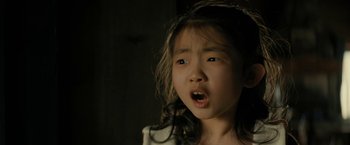 Movie still from “Knock at the Cabin” (2023), directed by M. Night Shyamalan – A little girl with long black hair is looking at the camera; Close Up shot, Over the shoulder angle