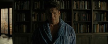 Movie still from “Knock at the Cabin” (2023), directed by M. Night Shyamalan – A man wearing a robe in front of a bookcase; Close Up shot, Low angle