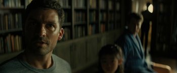 Movie still from “Knock at the Cabin” (2023), directed by M. Night Shyamalan – A man standing in front of a book shelf; Close Up shot, Low angle
