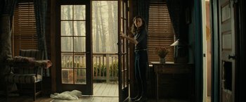 Movie still from “Knock at the Cabin” (2023), directed by M. Night Shyamalan – A woman standing in front of an open door; Wide shot, Low angle