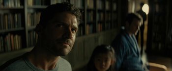 Movie still from “Knock at the Cabin” (2023), directed by M. Night Shyamalan – A person in a room with a book shelf in the background; Close Up shot, Low angle