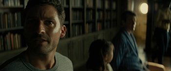 Movie still from “Knock at the Cabin” (2023), directed by M. Night Shyamalan – A person in a room with a book shelf in the background; Close Up shot, Low angle