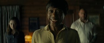 Movie still from “Knock at the Cabin” (2023), directed by M. Night Shyamalan – A person with short black hair smiles for the camera; Close Up shot, Over the shoulder angle