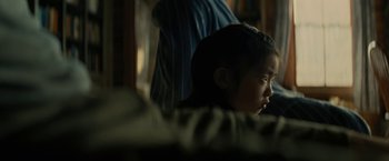 Movie still from “Knock at the Cabin” (2023), directed by M. Night Shyamalan – A little girl sitting in a chair looking at the camera; Close Up shot, Over the shoulder angle