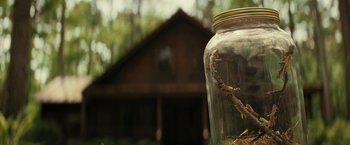 Movie still from “Knock at the Cabin” (2023), directed by M. Night Shyamalan – A glass jar filled with dirt on top of the ground; Close Up shot, Low angle