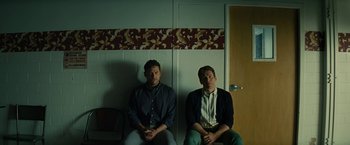 Movie still from “Knock at the Cabin” (2023), directed by M. Night Shyamalan – A couple of men sitting next to each other in a room; Medium shot, Low angle