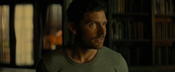 Movie still from “Knock at the Cabin” (2023), directed by M. Night Shyamalan – A person wearing a gray t - shirt; Close Up shot, Over the shoulder angle