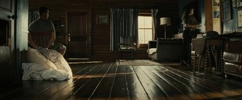 Movie still from “Knock at the Cabin” (2023), directed by M. Night Shyamalan – A living room with a couch , chair , and a window; Wide shot, Low angle